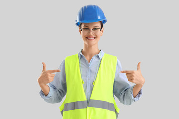 Female builder with earplugs on light background