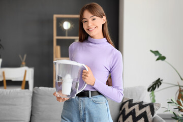 Young woman with water filter jug at home