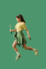 Female gardener with rakes jumping on green background