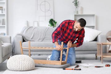 Young man assembling soft bench at home