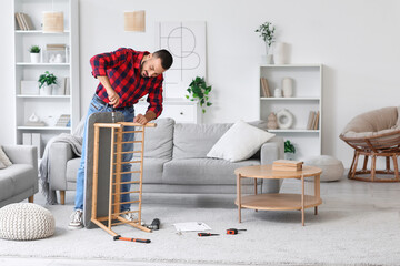 Young man with screwdriver assembling soft bench at home