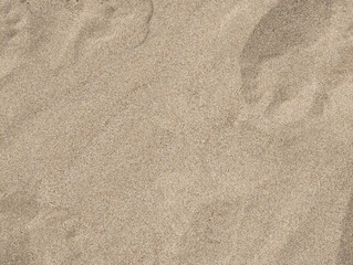 Top view and close-up texture of fine smooth dry Mediterranean beige beach sand with natural shadows, grainy textures, wave patterns across sandy surface, Valencia, Spain. Summer background wallpaper.