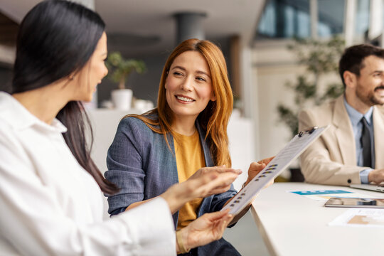 Two female executives discussing documents on a meeting at boardroom.