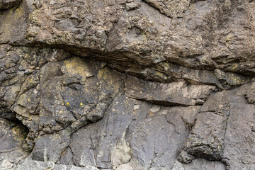 Weathered Coastal Cliff Rock Face with Cracks and Yellow Lichen Texture