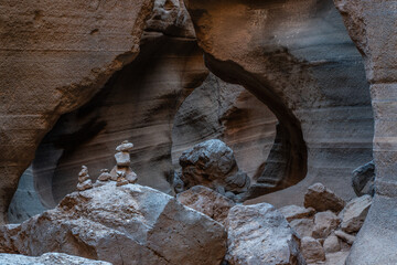 Small stone cairns standing on rocks inside a narrow canyon with colorful eroded walls