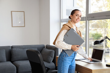 Young businesswoman working with laptop and folder in office