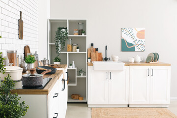 Kitchen counters with utensils and shelving unit in interior of kitchen