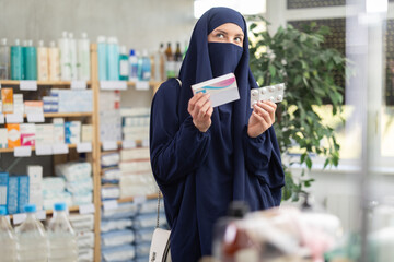 Young Muslim woman in traditional islamic dress and niqab covering face except eyes, carefully...