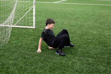 Young boy smiling while sitting on soccer field astro turf