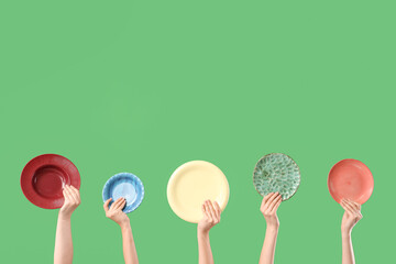 Young women holding different plates on green background