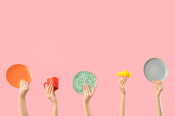 Female hands with plates, cup and hand squeezer on pink background