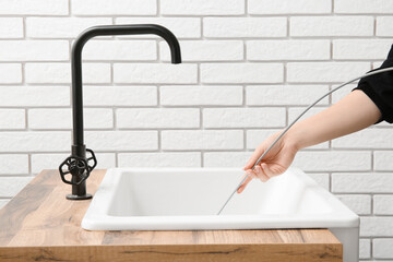 Woman cleaning drain with plumber's snake