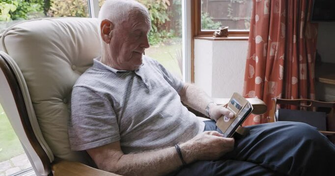 Elderly man, smartphone and relax in armchair enoying retirement in living room home with peace, quiet and stress free. Senior person, cellphone and scroll social media online for news entertainment
