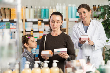 Woman with a child buys paracetamol, reads the instructions on the package and consults with a...