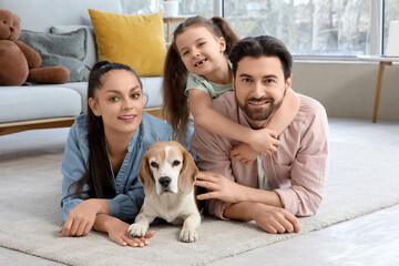 Cute little girl with her parents and Beagle dog lying on carpet at home