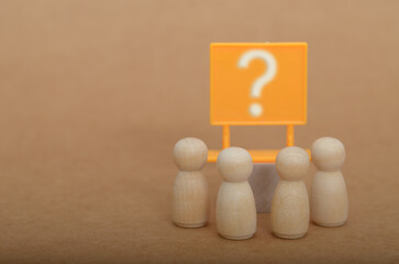 Mystery Ahead: Wooden Figures and a Prominent White Question Mark Sign