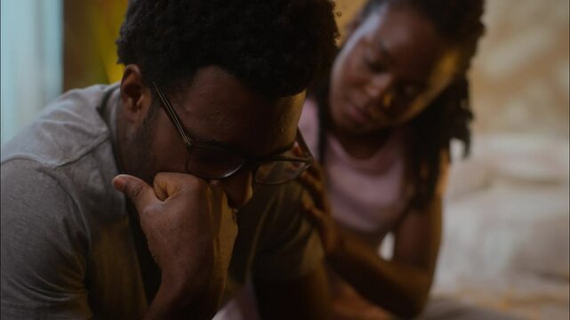 Family relationship couple support crying African American sad man husband sit bed suffering crisis pain worried breakdown impotence woman wife comforting calming spouse at home evening bedroom night