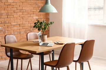 Dining table with laptop and plant in room