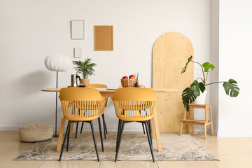 Interior of light room with dining table, lamp and palm plants