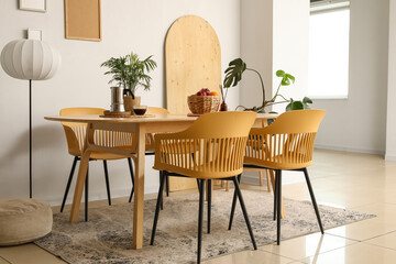 Interior of light room with dining table, lamp and palm plants