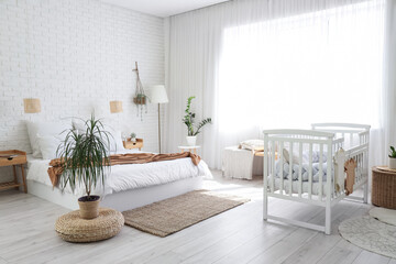 Interior of room with bed, baby crib and lamps