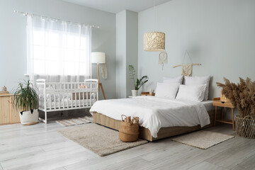 Interior of room with bed, baby crib and tables