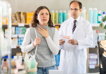 Fototapeta premium Young woman suffering from headache. Male pharmacist offering headache pain pills