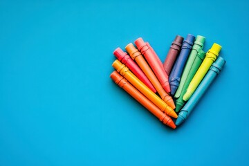 Obraz premium Rainbow Crayons Forming Heart on Blue Background