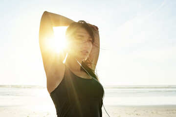 Ocean, earphones and woman stretching for fitness, healthy body and wellness at sunset. Arm warm up, music and athlete outdoor to prepare for exercise, training and ready for sports workout at beach