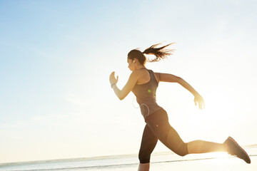 Woman, running and workout at beach with earphones, training or listen to music with mock up space...