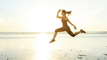 Woman, running and jumping for fitness at beach with energy, exercise and cardio training. Female athlete, air and runner with marathon performance of sports race, speed workout and competition goals