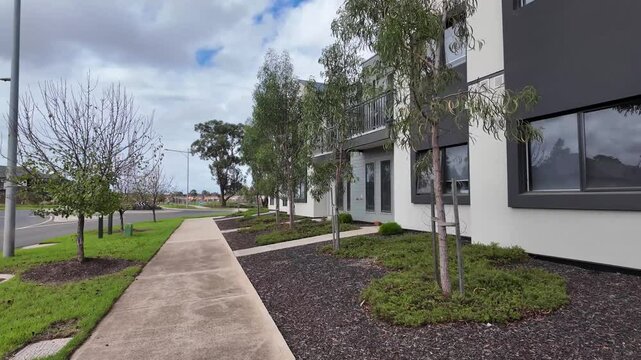 Modern townhouse development in Australia features contemporary architectural design with clean concrete pathways, newly planted native eucalyptus trees. Suburban townhomes in the neighborhood.