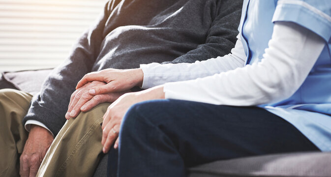 Caregiver holding a senior patients hand to support and help him in the retirement home. Closeup of a nurse helping a mature or retired man recover expressing care and compassion