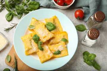 Delicious ravioli with cheese and basil served on grey table, flat lay