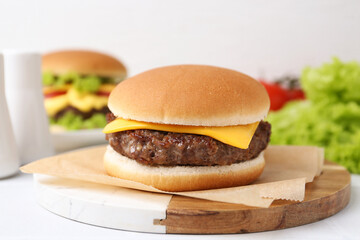 Cheeseburger with tasty patty on white table, closeup
