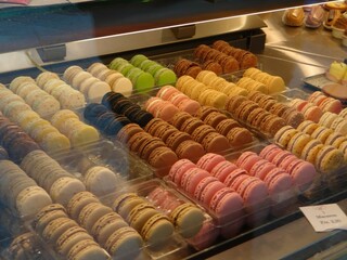 Delicious colorful macarons tempting customers from behind the glass of a display case in a French...