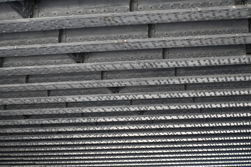 Steel girders in linear pattern. Underside of highway bridge.
