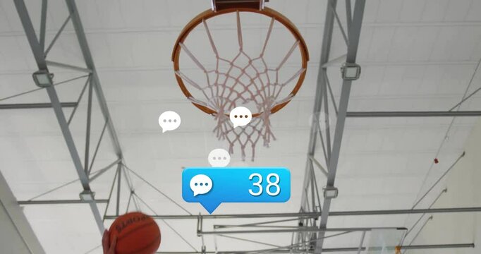 Male athlete dunking basketball in gym, showcasing chat bubble and comment icons in technology