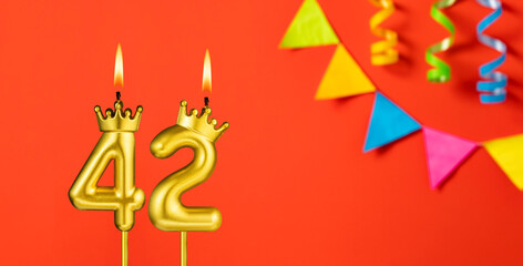 Number 42 birthday candle on an orange background with pennants