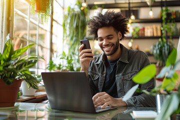 BUSTLING tech savvy man effortlessly multitasks by seamlessly switching between his smartphone and laptop computer to enjoy convenience and endless possibilities of online shopping    