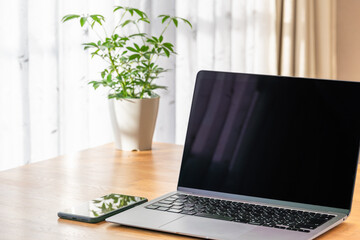 テーブルに置かれたノートパソコンとスマホ