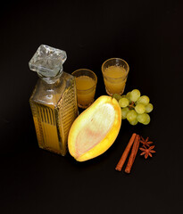 Homemade liqueur made from yellow mango and green grapes with cinnamon and anise in a crystal...