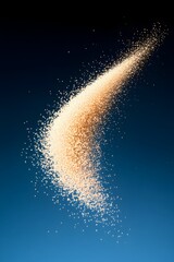 Fototapeta premium A beige powder swirls against a dark blue background, forming a dynamic, curved streak