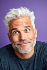 Obraz premium A charming and expressive man enjoying his portrait. Fashionable men's short dreads haircut - midlife white man with white hair. Purple solid background. Visual idea of style for aging men.