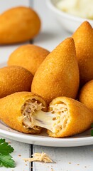 Crispy teardrop-shaped coxinhas filled with shredded chicken and catupiry cheese, golden fried crust, served on a banana leaf.