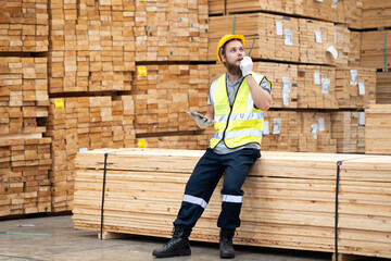 Fototapeta premium Male worker or engineer use walkie-talkie and inspecting timbers wood in warehouse. Concept of smart industry worker operating. Wood factories produce wood palate. 