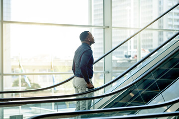 Escalator, airport and business black man for travel, commute and arrival in lobby for...