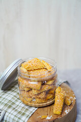 an open jar filled with cheese cookies and some cookies outside with gingham fabric and wooden...