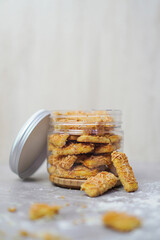 an open jar filled with cheese cookies and some cookies outside with cookie crumbs