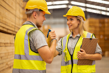 Team engineer carpenter wearing safety uniform and hard hat working holding clipboard checking quality of wooden products at workshop manufacturing. man and woman worker wood warehouse industry.